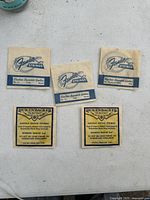 Five original packages of vintage guitar strings, three Fender and two Rickenbacker, displayed on a white surface.