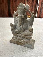 Full front view showing detailed carved elephant-headed figure seated with four arms holding symbolic objects, on a stone base.