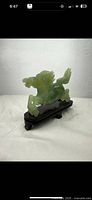 Side front view of green jade horse figurine on wooden base showing horse rearing stance with mane and tail details