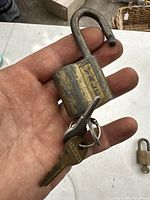 Close-up photo of vintage Yale padlock held in hand, showing wear and patina on metal body and shackle; key attached on keyring