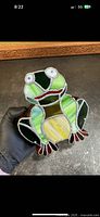 Front view of the stained glass frog piggy bank showing colorful stained glass pieces and design.