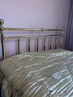 Photo shows the brass metal queen size bed frame headboard with vertical bars and rounded finials.