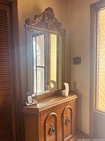 Front view of wooden hall cabinet with large ornate framed mirror and storage cabinet below