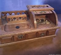 Wooden handmade jewellery box with multiple compartments, three small drawers, a curved roll-top section, and lattice design on one side. Some jewellery pieces inside one compartment.