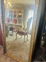 Full view of the large rectangular mirror showing its ornate gold carved frame and reflection of antique dining furniture
