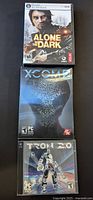 Front covers of three PC games: Alone in the Dark, XCom 2, and Tron 2.0 showing game artwork and titles.