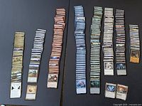 Collection of Magic: The Gathering cards sorted into multiple stacks featuring different card types and colors