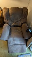Front view of brown riser recliner chair showing padded backrest, seat, armrests and attached control remote on right armrest.