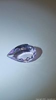 Single pear cut light pink purple amethyst gemstone, showing top and side facets clearly under light.