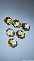 Six round natural citrine gemstones with double-sided checkerboard faceted cut, varying slight sizes but around 6mm each, clear yellow-orange color, laid on a neutral surface.