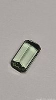 Close-up image of a natural green tourmaline octagon cut gemstone showing clear facets and pastel color.