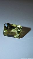 Top angled view of natural lemon citrine emerald cut gemstone showing clarity and color details.