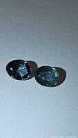 Pair of natural multicolored blue-green sapphires with fancy rose cut, showing clarity and color variations.