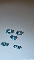 Several oval cut translucent seafoam blue zircon stones shown loose on a white background with good clarity and color.