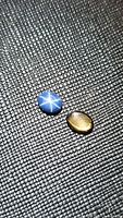 Pair of natural star sapphire gemstones on textured black material showing star effects