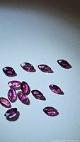 Several marquis cut, deep colored red/purple natural rubies arranged on white background to show size and color consistency.