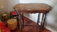 Front and angled view of the antique wooden table showing legs and top surface with engraved pattern.