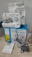 Brother XL-3750 sewing machine on top of original box with instruction manual and foot pedal beside it.