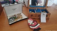 Photo of assorted costume jewelry in two boxes and a Santa Claus figurine on table