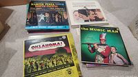Photo showing vinyl albums including South Pacific, Oklahoma!, and The Music Man show tune records in original Broadway cast editions.