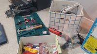 Multiple hand tools including hammer, pliers, wire cutters, screwdrivers, tape measure, and an electric drill with battery on floor near boxes.