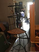 Front angle photo showing the black metal frame, wood shelves, and wire lower shelves of the bakers stand.