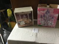 Photo showing two boxes on table: one for a multi-tiered cake stand, another for Pink Castle Cake Set.