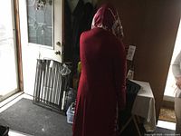 Red hooded cape with white spider web pattern, shown from rear on a person.