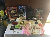 Front view of the lot showing all items on a white table including small collectibles, framed art, dream catchers, plush toy, and Pokey ball speaker.