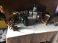 Full lot view showing all items on a white table including animal figurines, cast skull, Minions collectibles, two miniature chairs, wooden bucket, and glass jar