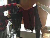 Photo of front and side views of the red and black gothic style Comicon shirt medium with sheer sleeves held up by two people