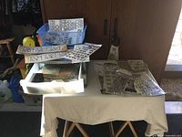 Photo showing variety of craft sticker sheets and embellishments spread over two tables, including rhinestone and gem stickers in packaging as well as loose sheets.