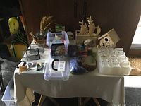 Overview of table with wooden pirate ship, birdhouse, plastic bins of craft items and supplies