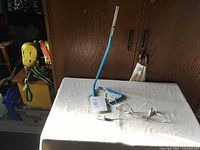 Blue LED desk lamp with flexible neck sitting on a white tablecloth, held upright with USB cord and inline switch visible.