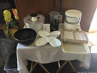 Overview of whole lot on table including salad spinner, steamer plus, food chopper, serving dish, egg tray, and colanders
