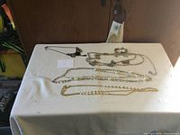 View of whole lot showing six jewelry items on white cloth including necklaces and bracelet.