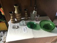 Photo showing all items on the table including three Antique ceramic jugs, two green glass bowls, two clear glass decorative pieces, and two small glass vessels.