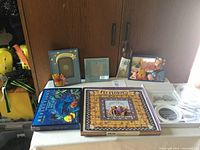 Photo showing layout of photo albums and picture frames on a shelf with wooden background; includes decorative items and multiple albums.