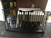 Front view of black metal double door pet gate showing the vertical bars and locking mechanism at top center.