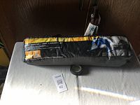 Side view of the sport shelter tent packed in its gray and yellow storage bag with product information printed on the fabric.