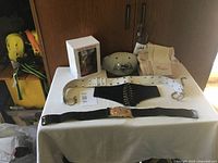 Photo showing two belts, Superman cap, Sparky bobblehead in box, and folded textile items on table.