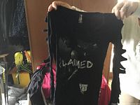 Front of black shirt showing 'Walking Dead' themed print and shredded sleeve detail.