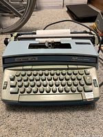 Front view of Coronet Super 12 electric typewriter showing keyboard, paper inserted, and main body.