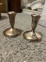 Two Empire sterling silver weighted candlestick holders on carpet background showing light tarnish.