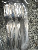 Set of forks in plastic wrappers showing starburst motif on handles