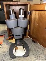 Front view of Bausch & Lomb stereomicroscope showing dual eyepieces and sturdy base, placed inside wooden storage case