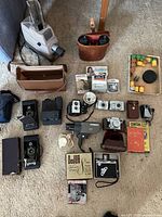 Overhead view of all lot items including cameras, projector, binoculars, accessories