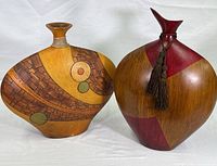 Two large wood carved vases placed side by side on white background showing overall shape, carving, and stained patterns.