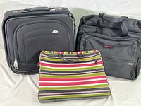 Three bags shown together: Samsonite black overnighter roller, black Tumi Broberg overnighter roller, striped laptop carry-on case