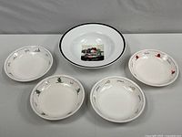 Set of four Pottery Barn pasta bowls with unique decorative rims depicting vegetables, hearts, and other small motifs in color on a white background.